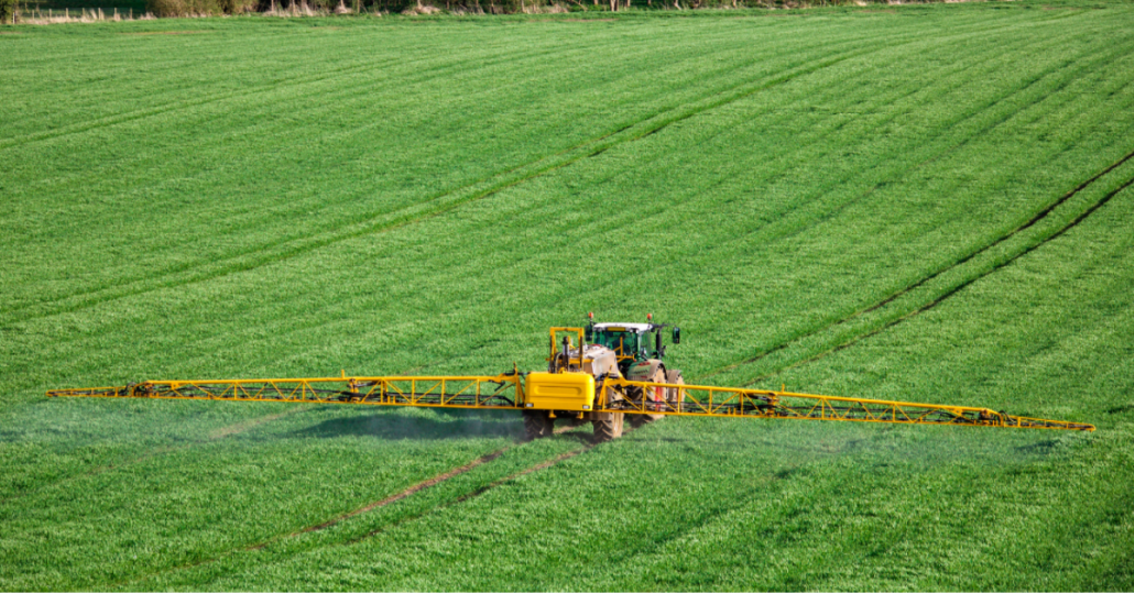 Tractor spraying weeds in grass field